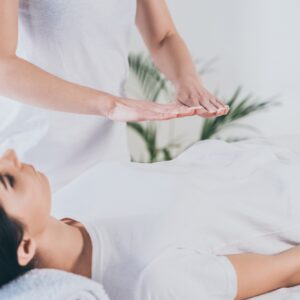 cropped shot of peaceful young woman receiving reiki healing treatment